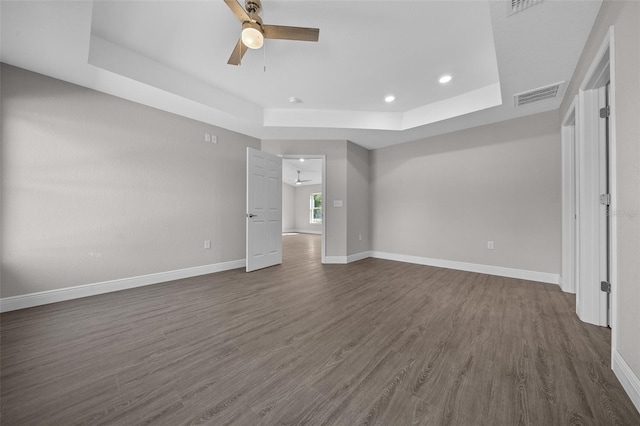 interior space featuring dark wood-type flooring, a raised ceiling, and ceiling fan