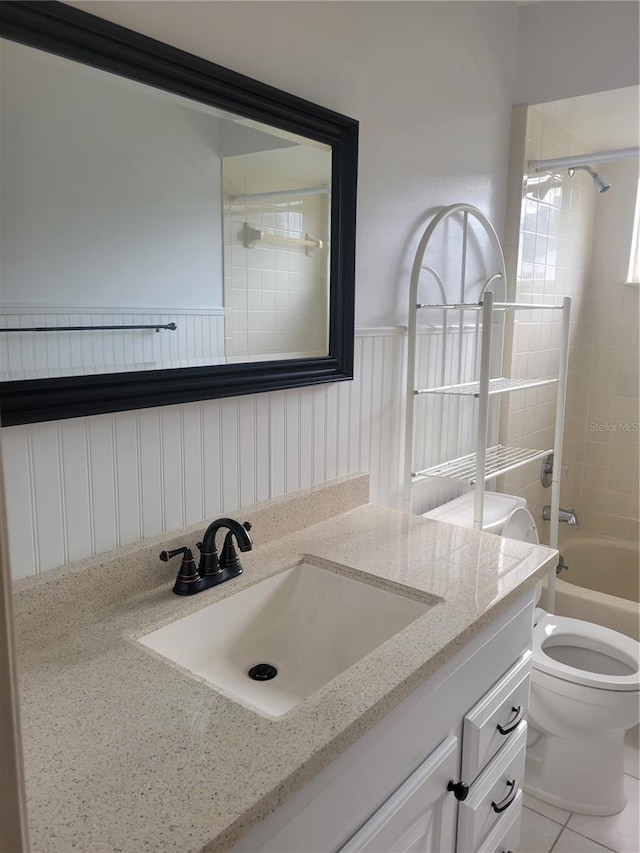 full bathroom featuring tiled shower / bath, vanity, toilet, and tile patterned floors