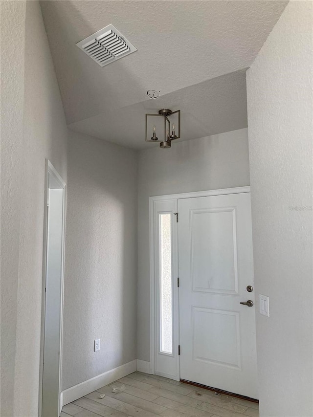 entryway featuring a healthy amount of sunlight, light hardwood / wood-style floors, and a textured ceiling