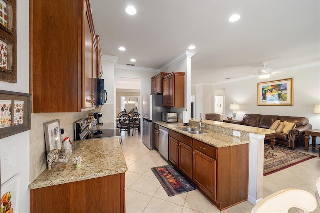 kitchen featuring sink, crown molding, appliances with stainless steel finishes, kitchen peninsula, and light stone countertops