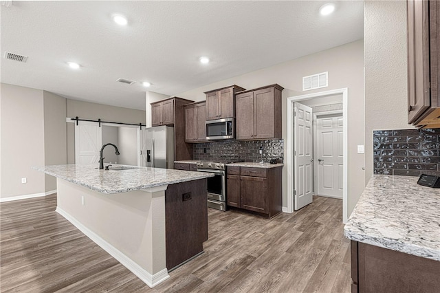 kitchen with sink, hardwood / wood-style flooring, stainless steel appliances, and a barn door