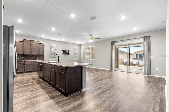 kitchen featuring stainless steel refrigerator, sink, an island with sink, and hardwood / wood-style flooring