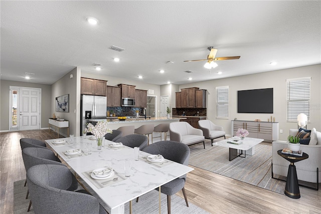 dining space featuring ceiling fan, a textured ceiling, and light wood-type flooring