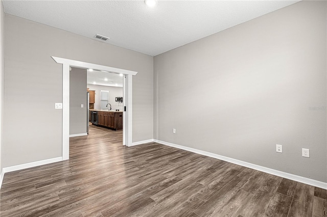 spare room with dark hardwood / wood-style flooring, sink, and a textured ceiling