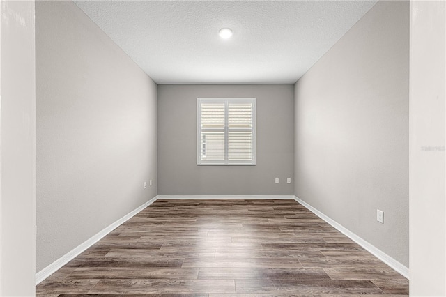 unfurnished room featuring dark wood-type flooring and a textured ceiling