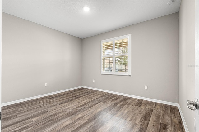 empty room featuring dark wood-type flooring and a textured ceiling