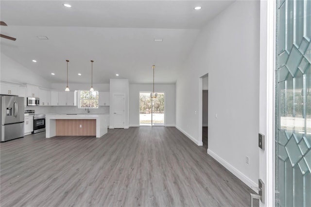 kitchen featuring decorative light fixtures, white cabinetry, a center island, light hardwood / wood-style floors, and stainless steel appliances