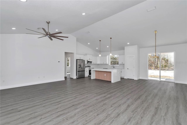 unfurnished living room featuring dark hardwood / wood-style flooring, ceiling fan with notable chandelier, and high vaulted ceiling