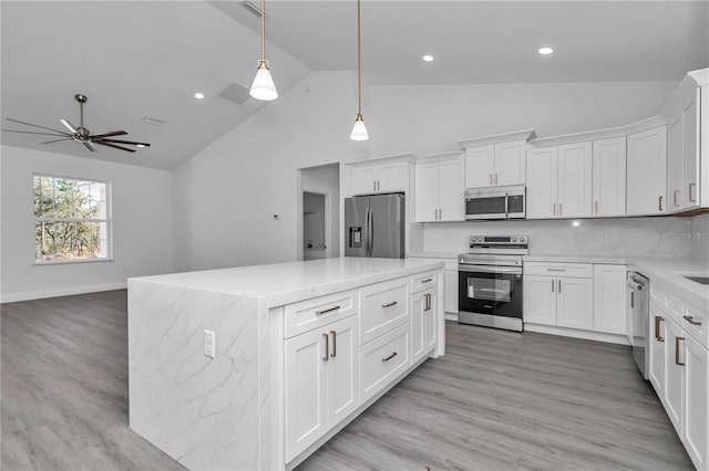 kitchen with a kitchen island, pendant lighting, white cabinets, backsplash, and stainless steel appliances