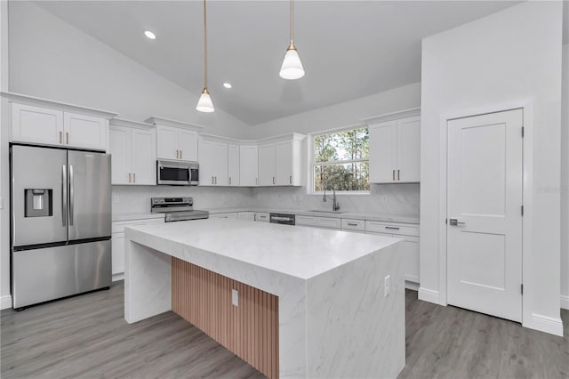 kitchen with pendant lighting, stainless steel appliances, white cabinets, and a kitchen island