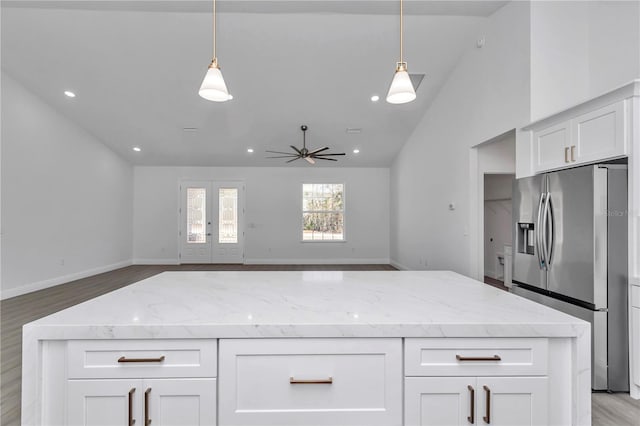 kitchen with pendant lighting, stainless steel fridge, light stone countertops, white cabinets, and french doors