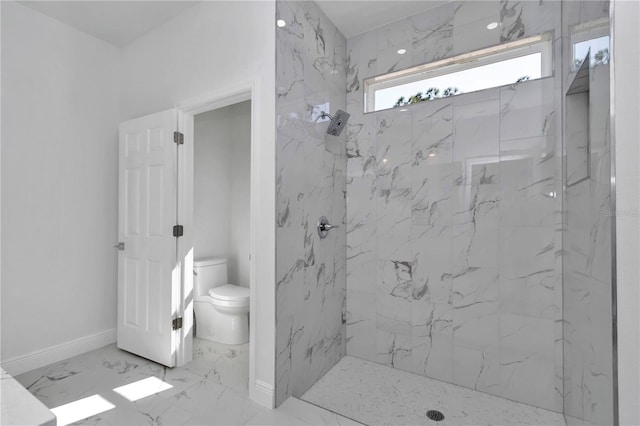 bathroom with a tile shower and toilet