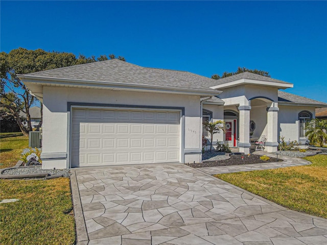 view of front of house with a garage, a front yard, and central air condition unit