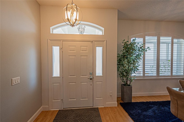 foyer with wood-type flooring, a textured ceiling, and an inviting chandelier