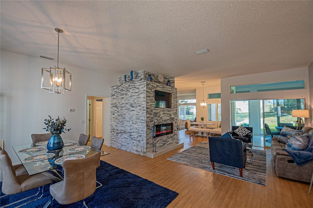 dining area featuring hardwood / wood-style flooring, a healthy amount of sunlight, and a stone fireplace