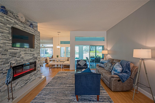 living room featuring a stone fireplace, a textured ceiling, and hardwood / wood-style flooring