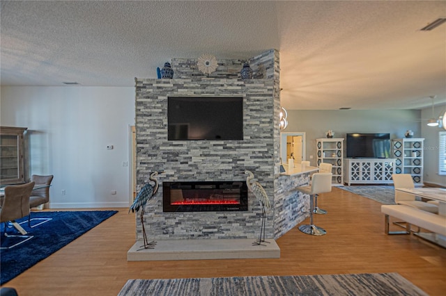 living room with hardwood / wood-style flooring, a textured ceiling, and a fireplace