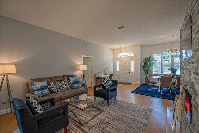 living room featuring hardwood / wood-style floors, a notable chandelier, and a textured ceiling