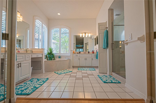 bathroom with tile patterned flooring, vanity, independent shower and bath, and a textured ceiling