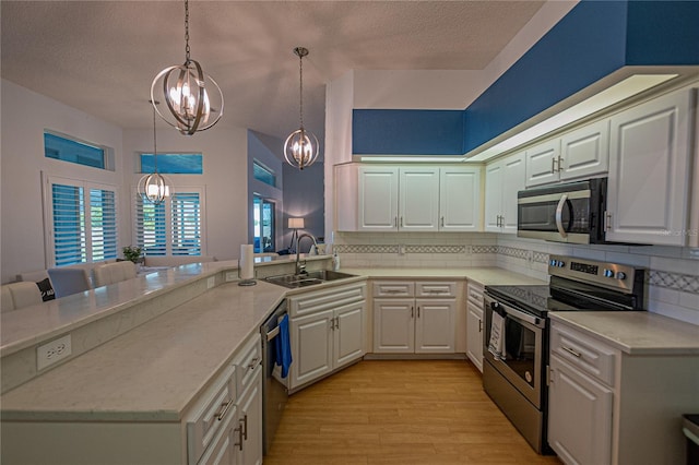 kitchen featuring stainless steel appliances, white cabinetry, sink, and decorative light fixtures