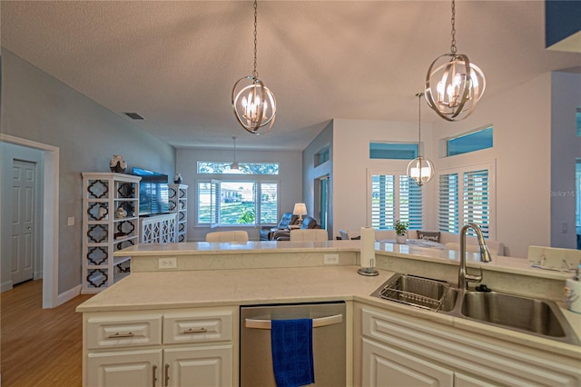 kitchen featuring sink, light hardwood / wood-style flooring, dishwasher, an inviting chandelier, and hanging light fixtures