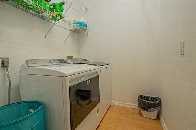 clothes washing area featuring washing machine and dryer and light wood-type flooring