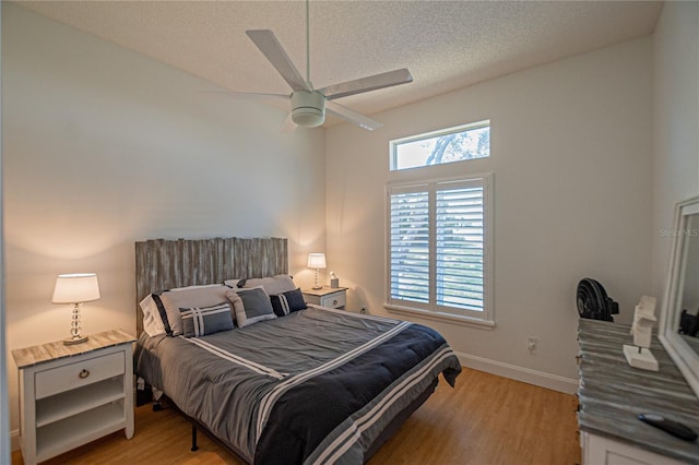 bedroom with ceiling fan, a textured ceiling, and light wood-type flooring