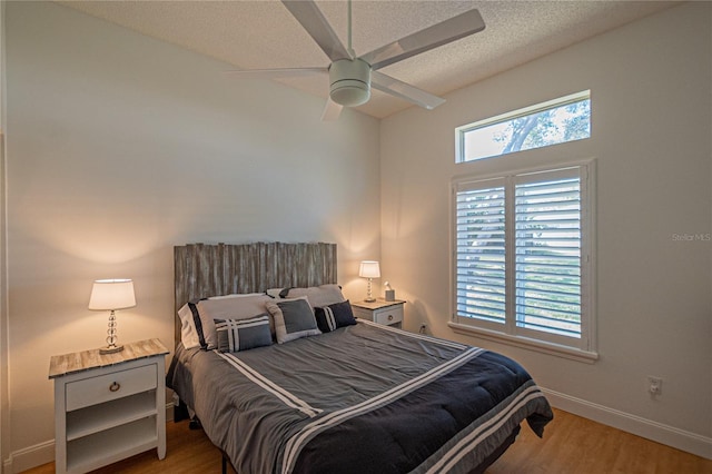 bedroom with multiple windows, ceiling fan, light hardwood / wood-style floors, and a textured ceiling