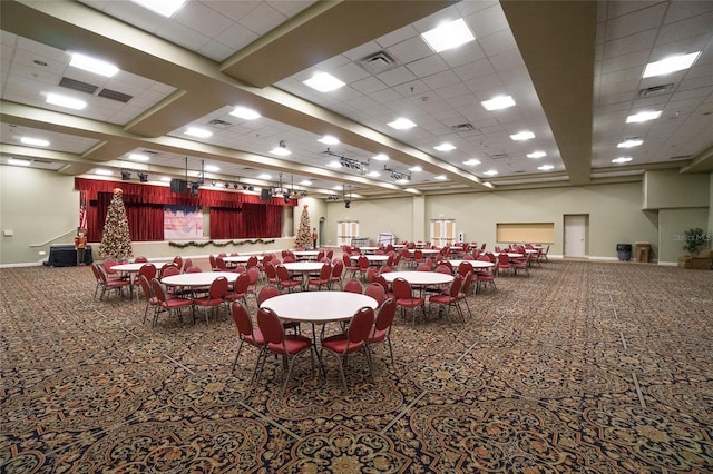 carpeted dining area with a paneled ceiling