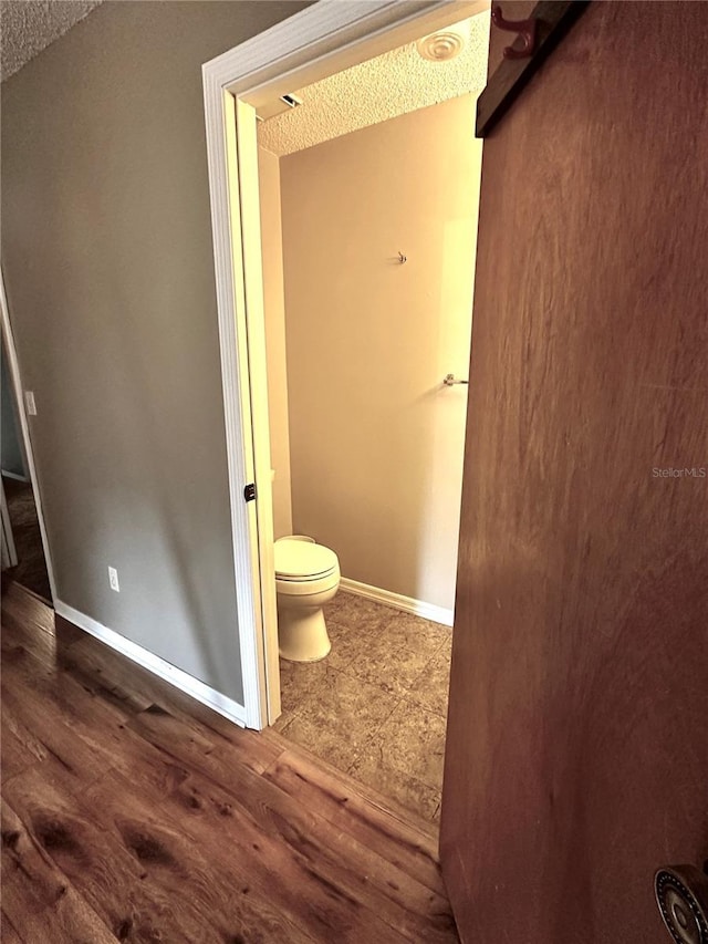 bathroom with toilet, hardwood / wood-style floors, and a textured ceiling