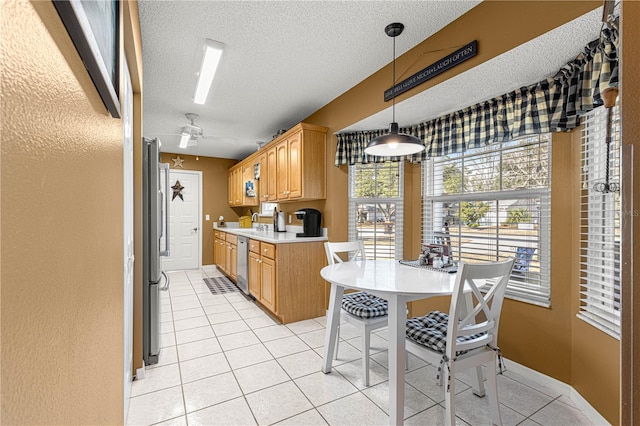 kitchen featuring appliances with stainless steel finishes, hanging light fixtures, light tile patterned floors, ceiling fan, and a textured ceiling