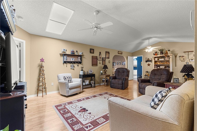 living room with lofted ceiling, hardwood / wood-style flooring, a textured ceiling, and ceiling fan