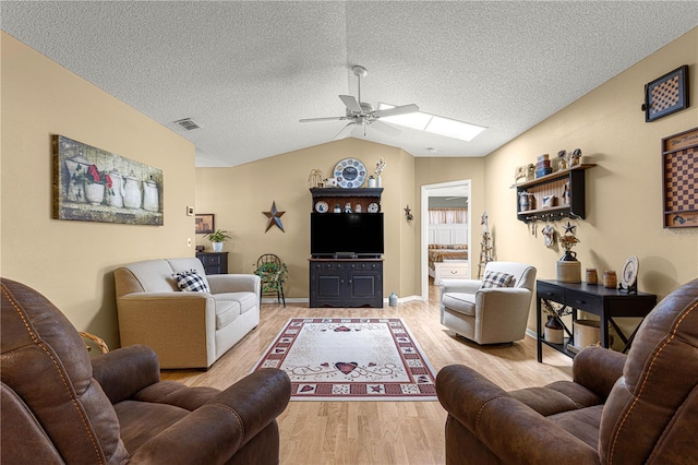 living room featuring ceiling fan, lofted ceiling, a textured ceiling, and light wood-type flooring