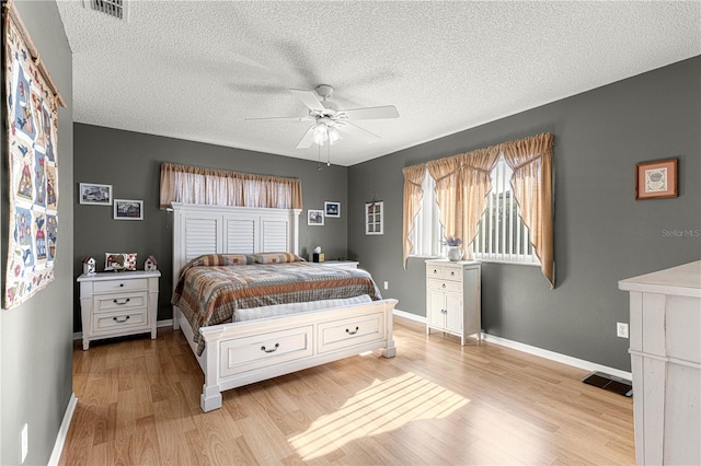 bedroom featuring ceiling fan, a textured ceiling, and light wood-type flooring