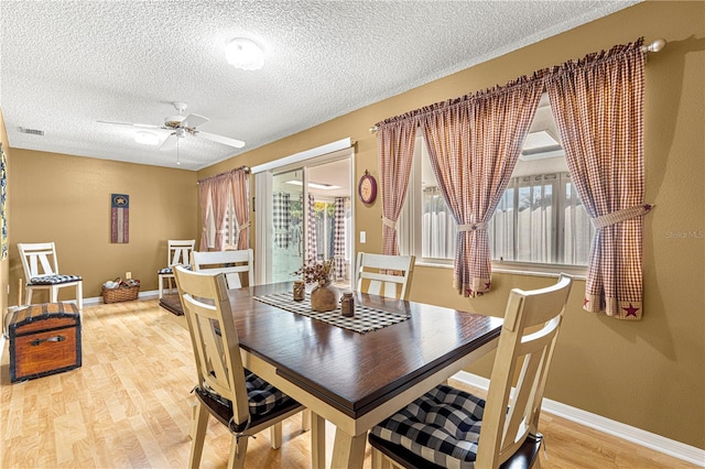 dining area featuring wood-type flooring, a textured ceiling, and ceiling fan