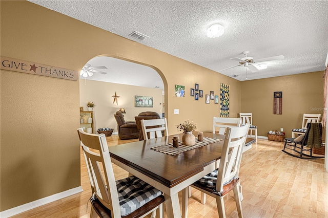 dining space with light wood-type flooring, a textured ceiling, and ceiling fan