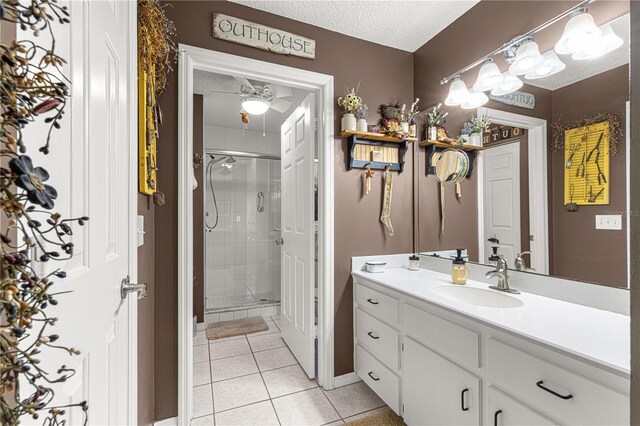 bathroom with tile patterned floors, an enclosed shower, a textured ceiling, vanity, and ceiling fan