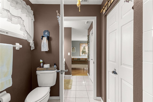 bathroom featuring toilet, tile patterned flooring, and a textured ceiling