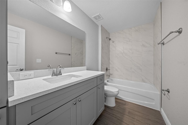 full bathroom with tiled shower / bath, hardwood / wood-style floors, vanity, and toilet