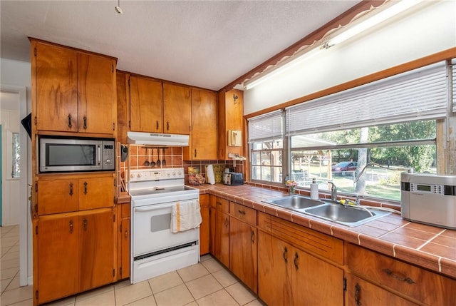 kitchen featuring sink, backsplash, white electric range oven, tile counters, and plenty of natural light