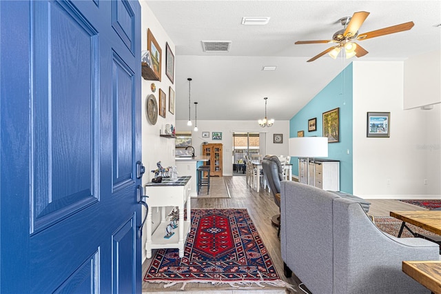 living room with vaulted ceiling, sink, wood-type flooring, and ceiling fan with notable chandelier