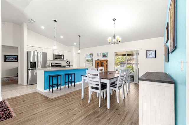 dining room featuring sink, a notable chandelier, light hardwood / wood-style flooring, and high vaulted ceiling