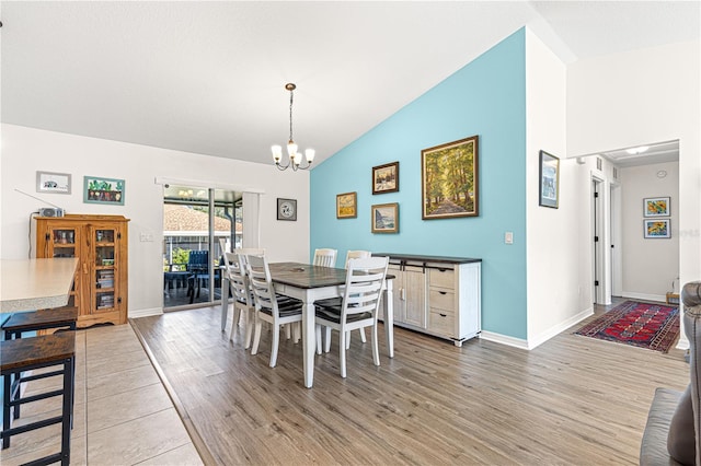 dining room with hardwood / wood-style flooring, a notable chandelier, and high vaulted ceiling