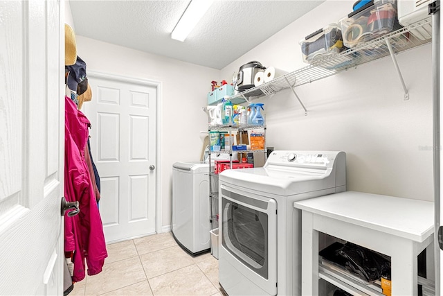 clothes washing area with light tile patterned floors, washer and clothes dryer, and a textured ceiling