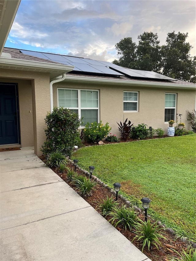 view of property exterior featuring a lawn and solar panels