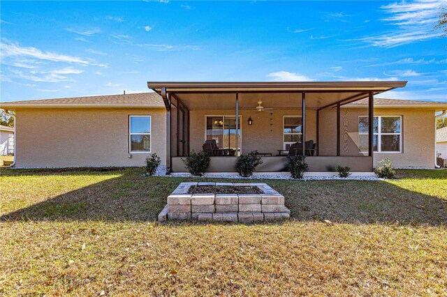 rear view of house featuring a yard, a fire pit, a sunroom, and ceiling fan