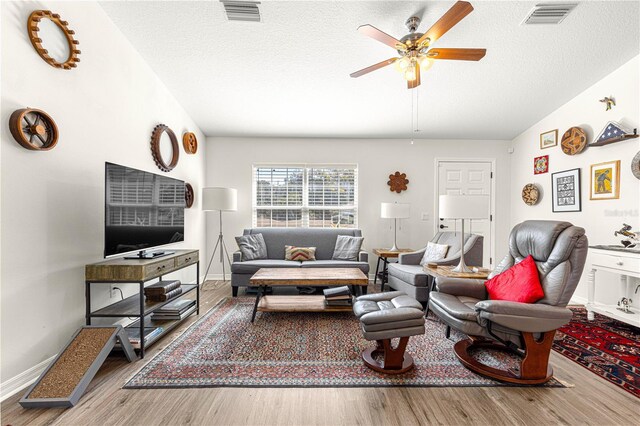 living room featuring lofted ceiling, ceiling fan, a textured ceiling, and light wood-type flooring