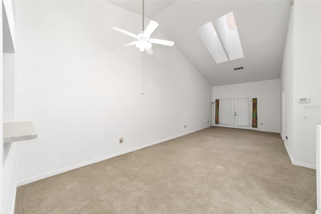 empty room with light carpet, a skylight, high vaulted ceiling, and ceiling fan