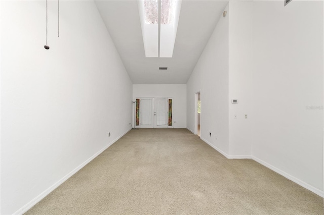 empty room with high vaulted ceiling and light colored carpet