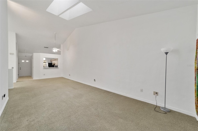 unfurnished living room featuring high vaulted ceiling, a skylight, light colored carpet, and ceiling fan